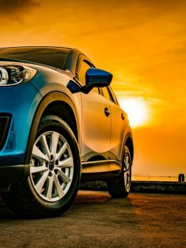 Blue compact SUV car with sport and modern design parked on concrete road by the sea at sunset. Environmentally friendly technology. Business success concept.