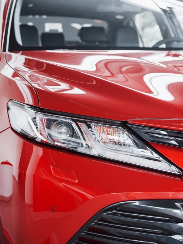 Headlights of the new red car, in the car dealership